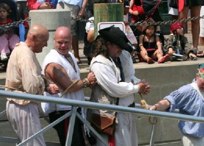 Blackbeard's captured pirates being lead off 
          the dock