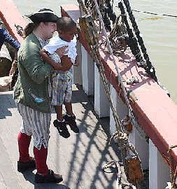 Michael holding a kid up to look over the side of the ship