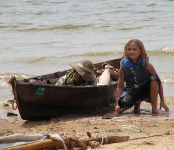 Bradley crouched on the beach by a boat