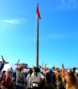 The pirates cheer the raised pirate flag.